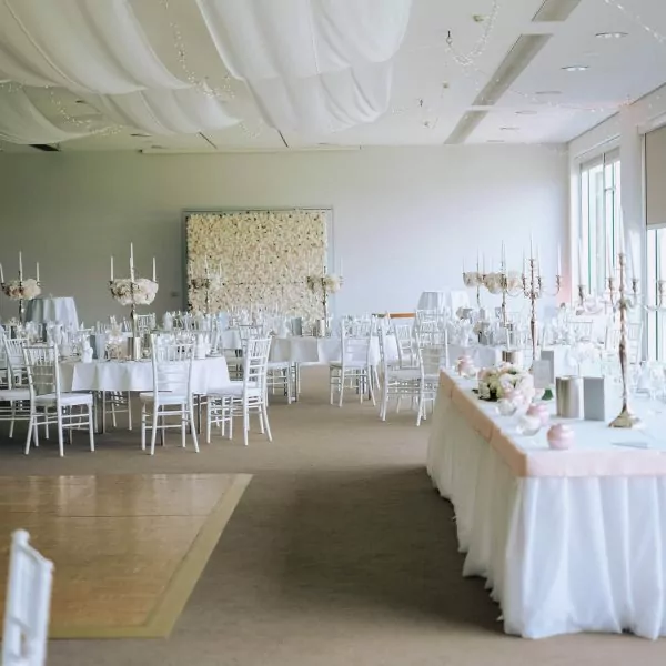 Eleganter Hochzeitssaal mit wei&szlig;en St&uuml;hlen, gedeckten Tischen, Blumenarrangements und Kerzenleuchtern, ATLANTIC Hotel Bremen.