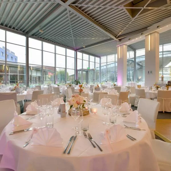 Eleganter, lichtdurchfluteter Bankettsaal mit festlich gedeckten Tischen und Blumenarrangements im ATLANTIC Hotel Bremen.